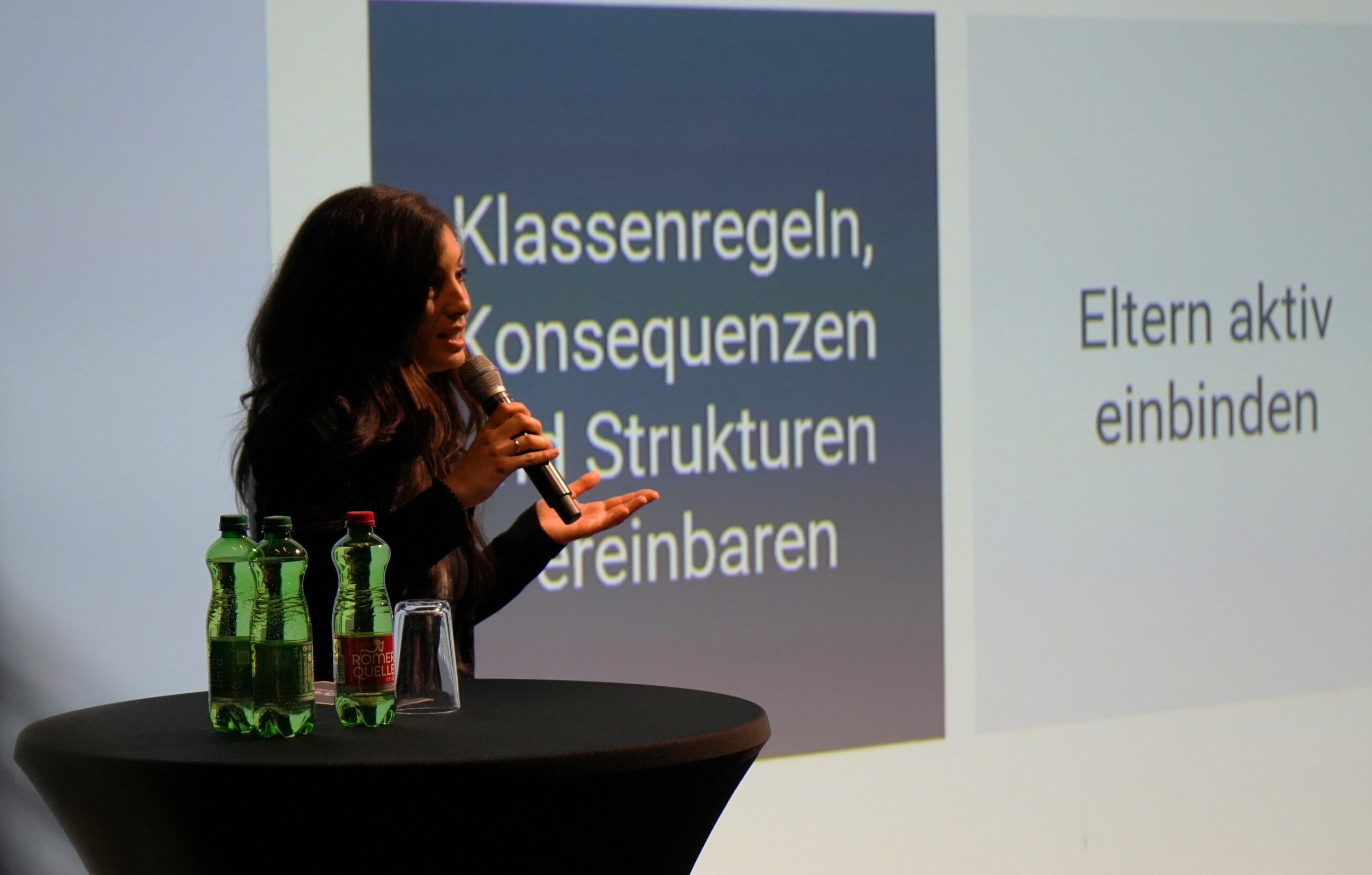 COOL Lab Mitarbeiterin Marina auf einer Bühne vor einer Präsentation.