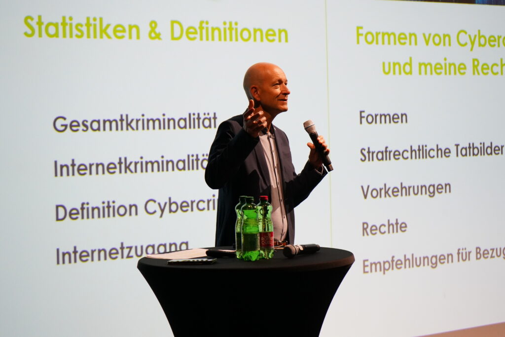 Jurist auf einer Bühne vor einer Leinwand mit verschiedenen rechtlichen Definitionen.